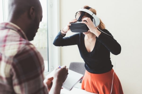 woman wearing VR headset and man taking notes